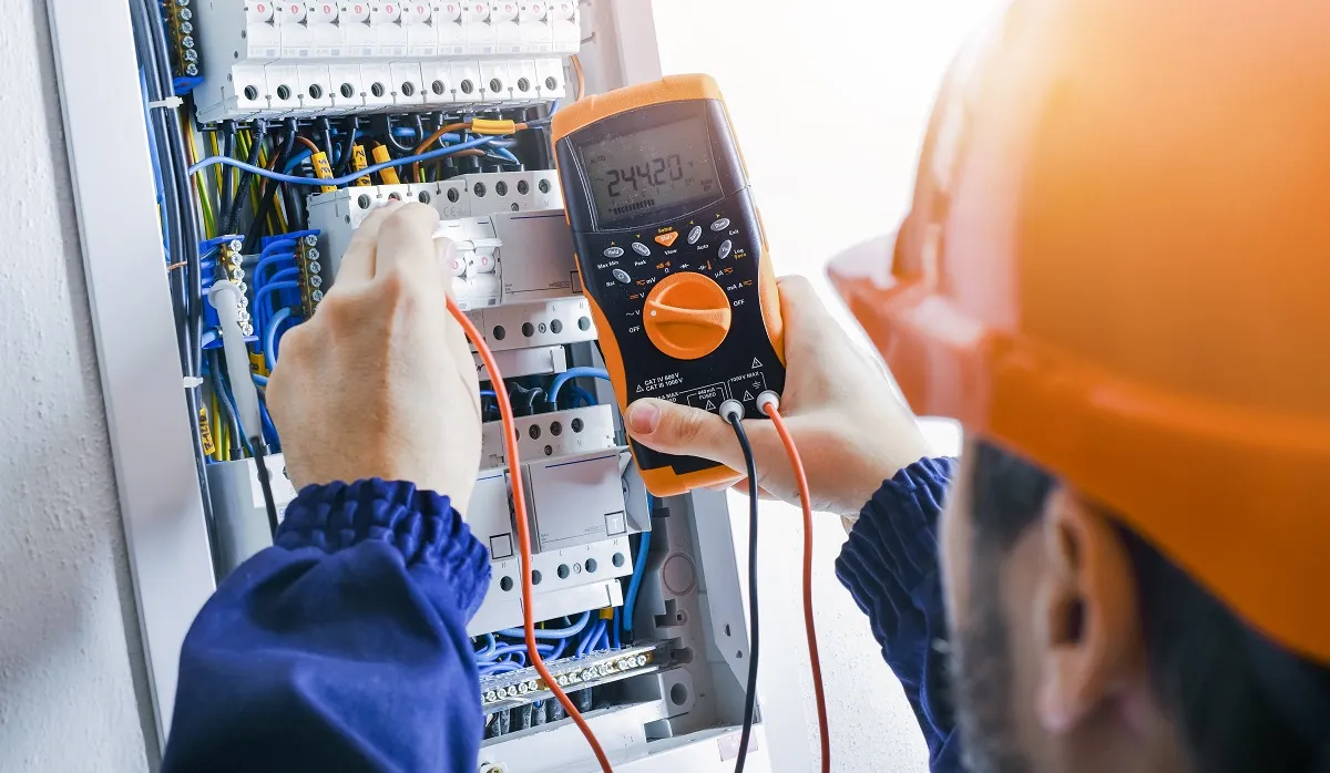 An electrician testing an open consumer unit